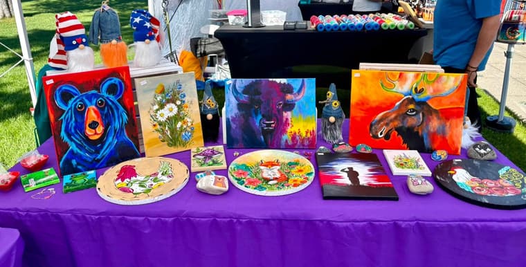 Original paintings and painted rocks laid out on a market table